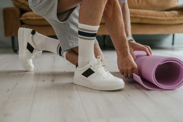 A close-up of a yoga mat on a dark wooden floor.